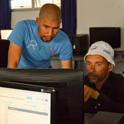 Projects Abroad volunteer helping a student with their computer skills at one of our volunteer IT teaching placements in South Africa Volunteer helping a students with his assignment during IT teaching experience in South Africa
